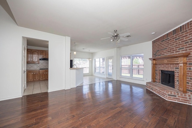 11805 Chaparral Dr, Frisco, TX 75035 - unfurnished living room featuring wood finished floors, a ceiling fan, a brick fireplace, and plenty of natural light