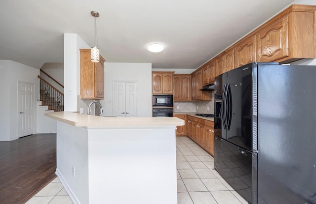 11805 Chaparral Dr, Frisco, TX 75035 - kitchen featuring black appliances, a peninsula, light tile patterned floors, tasteful backsplash, and light countertops