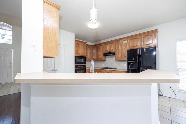 11805 Chaparral Dr, Frisco, TX 75035 - kitchen featuring black appliances, under cabinet range hood, backsplash, light countertops, and a peninsula