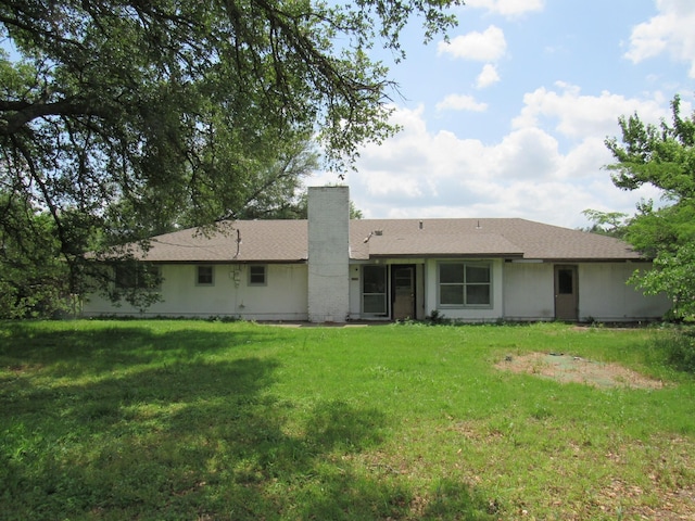 rear view of property featuring a chimney and a lawn