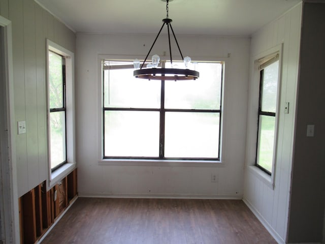 unfurnished dining area with an inviting chandelier and wood finished floors