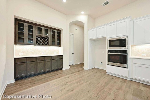 11745 Edgewood Dr, Justin, TX 76247 - kitchen with built in microwave, oven, visible vents, arched walkways, and decorative backsplash