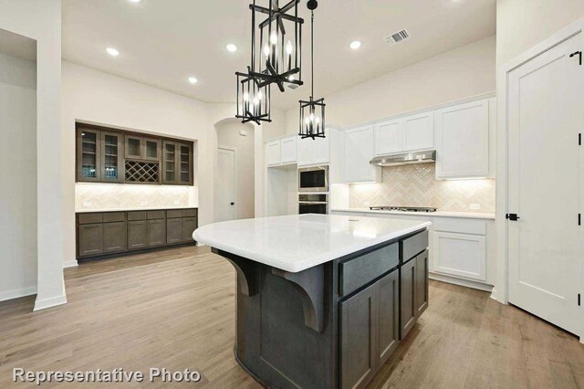 11745 Edgewood Dr, Justin, TX 76247 - kitchen featuring white cabinetry, decorative backsplash, visible vents, and under cabinet range hood