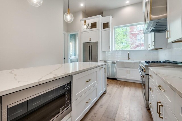 235 E Nash St Unit 118, Grapevine, TX 76051 - kitchen with a sink, wall chimney exhaust hood, high quality appliances, backsplash, and white cabinets