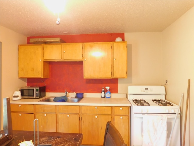 kitchen featuring stainless steel microwave, a sink, light countertops, and white gas stove