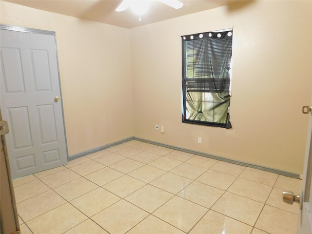 empty room with ceiling fan, light tile patterned flooring, and baseboards