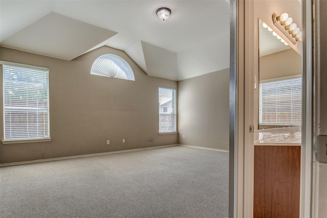 carpeted spare room with baseboards and lofted ceiling