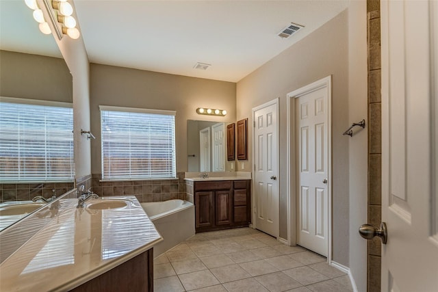 bathroom featuring a sink, two vanities, a bath, visible vents, and tile patterned flooring
