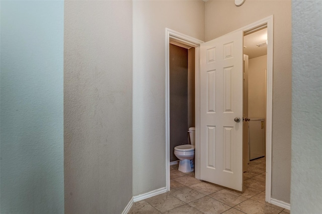 hallway featuring baseboards and light tile patterned flooring
