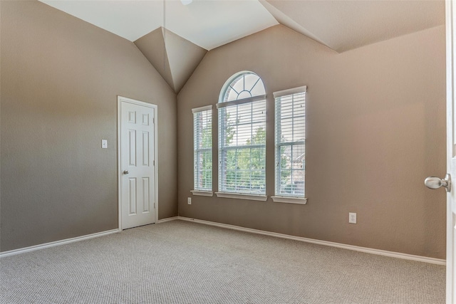 spare room with vaulted ceiling, light colored carpet, and baseboards