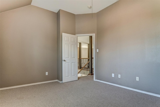 empty room with baseboards, lofted ceiling, and carpet floors
