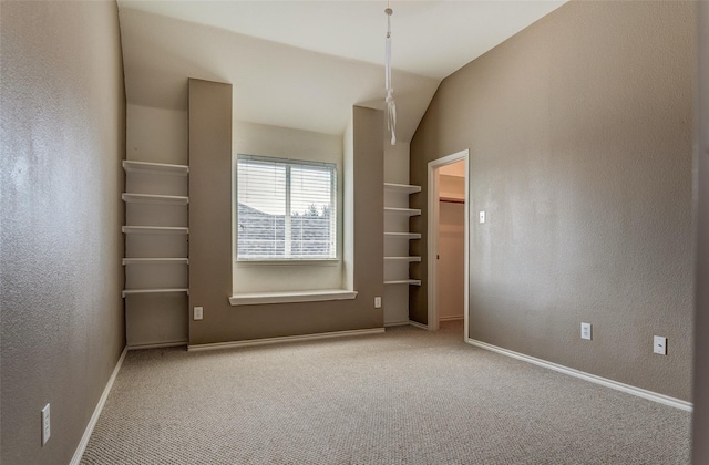 carpeted empty room with baseboards and vaulted ceiling