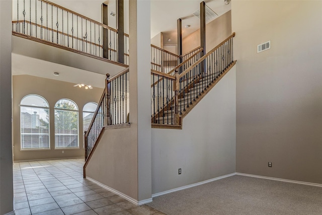 stairway with visible vents, baseboards, a high ceiling, and carpet floors