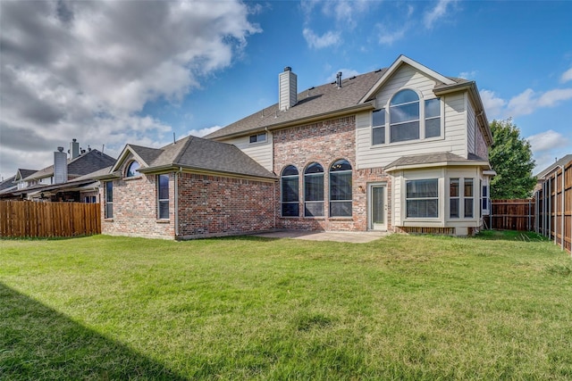 back of house with a fenced backyard, a chimney, brick siding, and a lawn