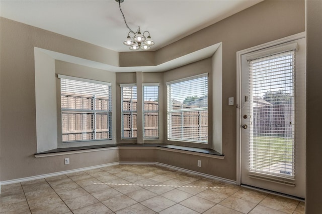 unfurnished dining area featuring an inviting chandelier, light tile patterned floors, and baseboards