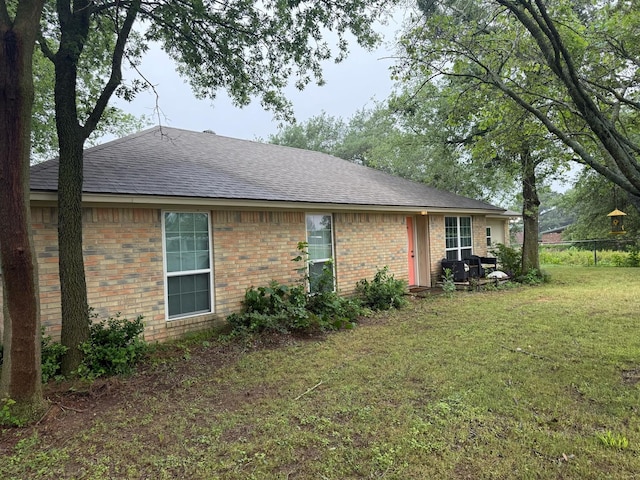 1104 County Road 701, Cleburne, TX 76031 - view of property exterior featuring fence, a shingled roof, brick siding, and a lawn