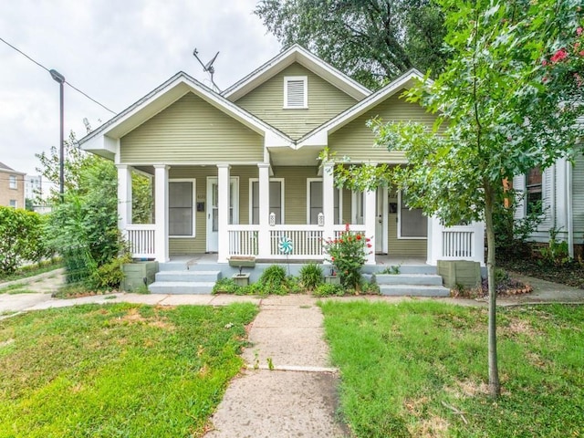 bungalow-style house featuring covered porch and a front lawn