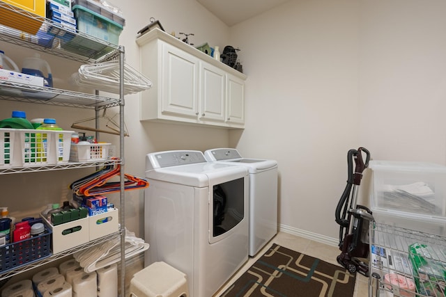clothes washing area featuring baseboards, washing machine and dryer, light tile patterned flooring, and cabinet space