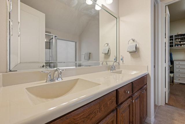 bathroom with a sink, double vanity, a shower stall, and tile patterned flooring