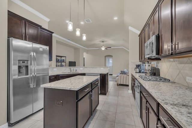 kitchen with appliances with stainless steel finishes, dark brown cabinets, tasteful backsplash, and a ceiling fan
