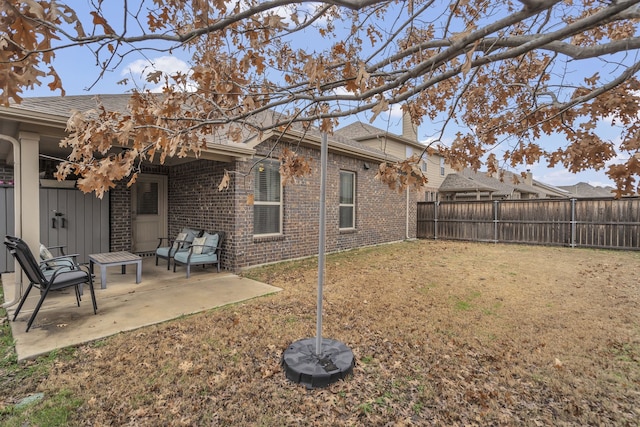 rear view of house with a chimney, a fenced backyard, a yard, brick siding, and a patio area