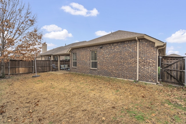 rear view of house featuring a fenced backyard, a patio, a yard, and brick siding