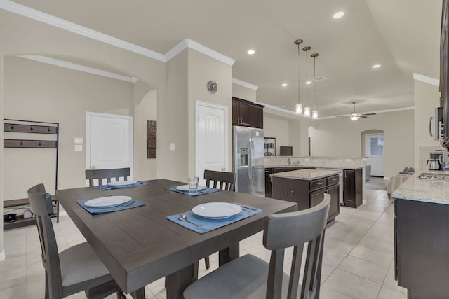 dining area with crown molding, arched walkways, a ceiling fan, and light tile patterned floors
