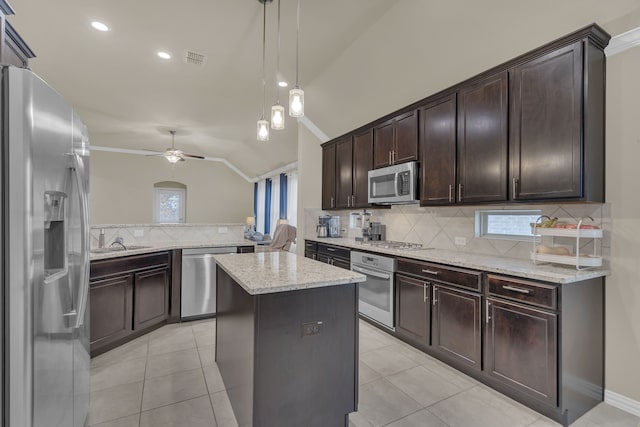 kitchen featuring stainless steel appliances, ceiling fan, decorative backsplash, a kitchen island, and lofted ceiling