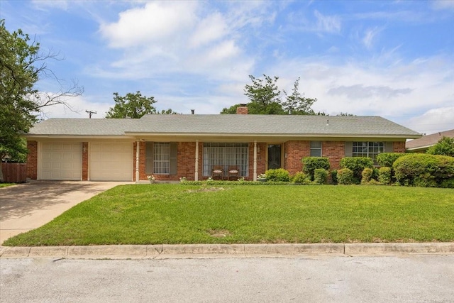 ranch-style home featuring an attached garage, a chimney, concrete driveway, a front yard, and brick siding