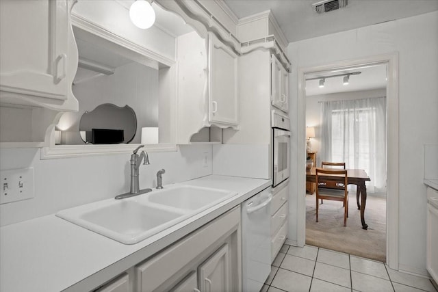 kitchen with white dishwasher, light tile patterned flooring, visible vents, a sink, and light countertops
