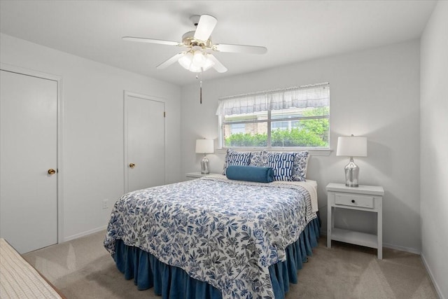 bedroom featuring light colored carpet, baseboards, and a ceiling fan
