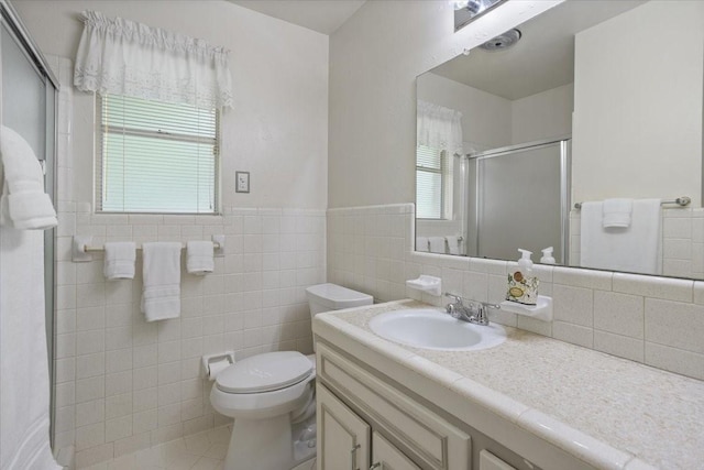 bathroom with a stall shower, tile walls, toilet, wainscoting, and vanity