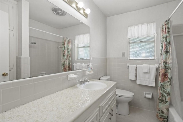 bathroom with toilet, a shower with curtain, tile patterned floors, tile walls, and vanity