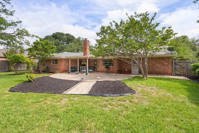 back of property featuring a chimney, a yard, brick siding, fence, and a patio area