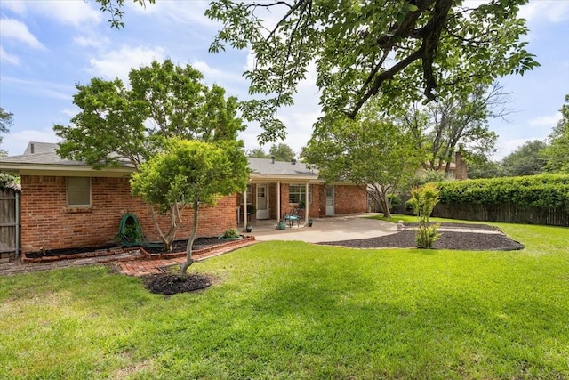 back of house featuring a lawn, a patio, brick siding, and fence