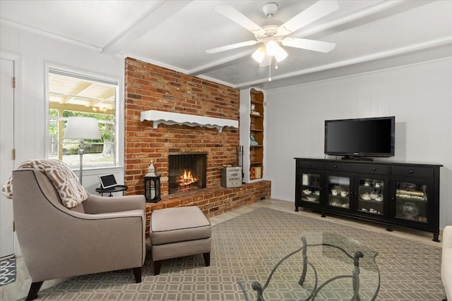 living room with beamed ceiling, a fireplace, a ceiling fan, and ornamental molding