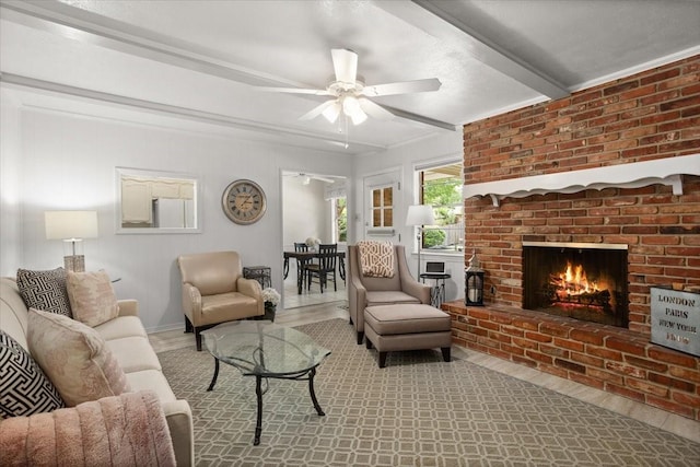 living room featuring a ceiling fan, a fireplace, beam ceiling, and wood finished floors