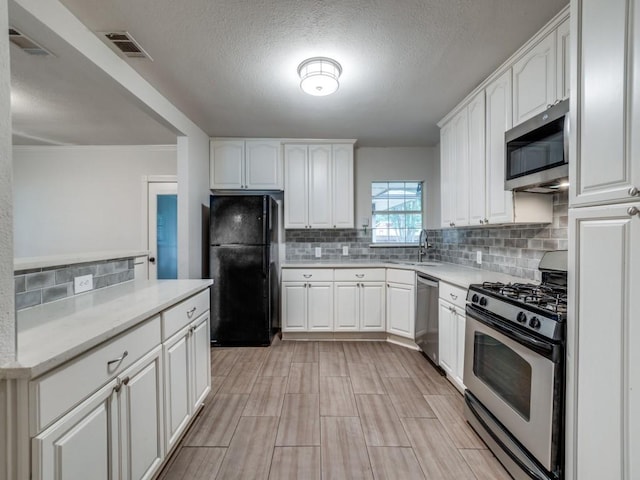 3703 Clover Ln, Dallas, TX 75220 - kitchen featuring visible vents, a sink, white cabinetry, backsplash, and stainless steel appliances