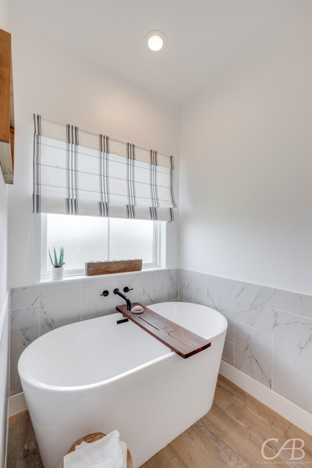 7001 Breezeway Dr, Abilene, TX 79606 - bathroom featuring tile walls, a soaking tub, wainscoting, and wood finished floors