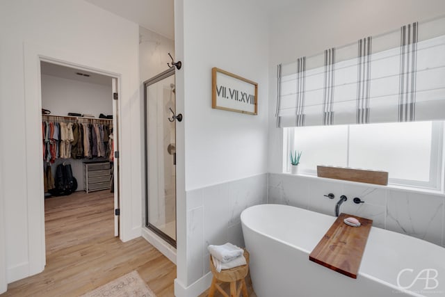 7001 Breezeway Dr, Abilene, TX 79606 - full bathroom with wood finished floors, a walk in closet, a freestanding bath, visible vents, and a shower stall