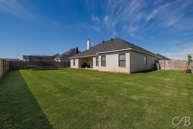 7001 Breezeway Dr, Abilene, TX 79606 - rear view of property featuring a chimney, a trampoline, a fenced backyard, and a lawn