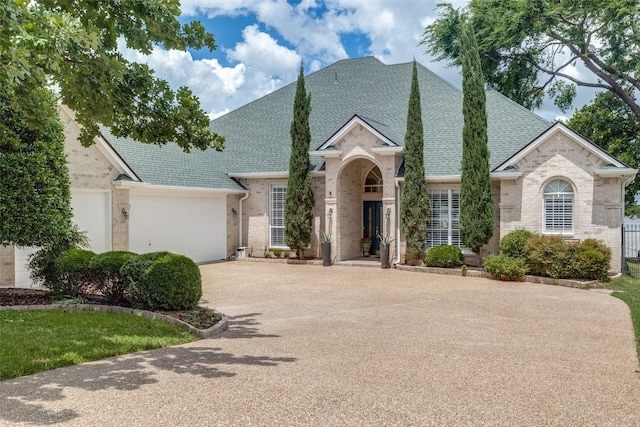 traditional-style house featuring a shingled roof, brick siding, concrete driveway, and a garage