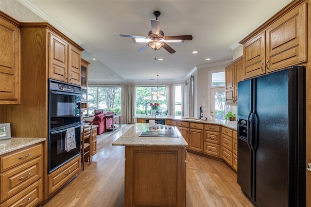 kitchen featuring black appliances, a peninsula, ornamental molding, healthy amount of natural light, and light wood-type flooring