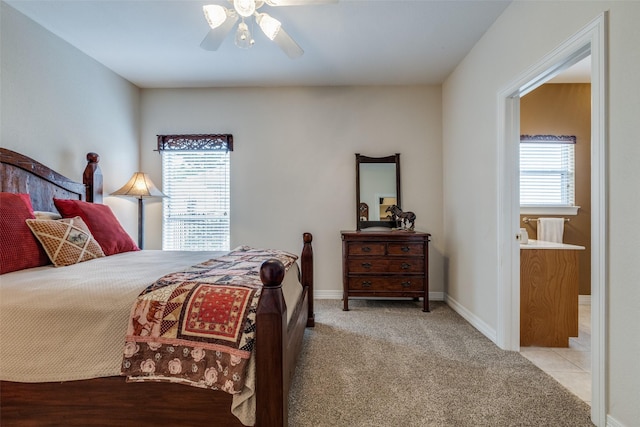 carpeted bedroom featuring multiple windows, a ceiling fan, ensuite bath, and baseboards