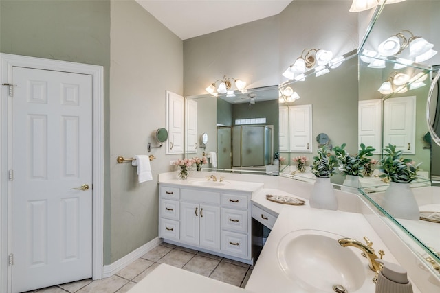full bath featuring a stall shower, a chandelier, two vanities, tile patterned floors, and baseboards