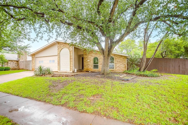 view of front of house with fence, brick siding, driveway, a garage, and a front lawn