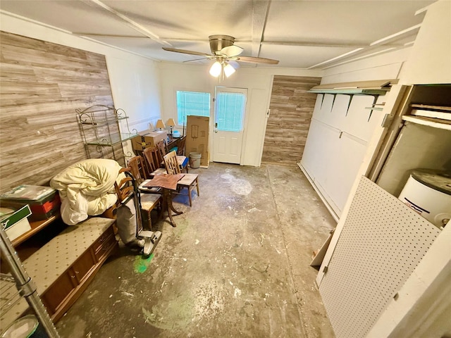 interior space featuring a ceiling fan, unfinished concrete floors, and wood walls