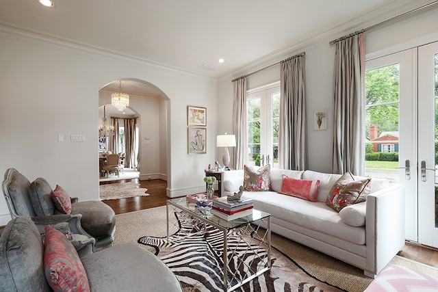 living area featuring wood finished floors, baseboards, arched walkways, ornamental molding, and recessed lighting