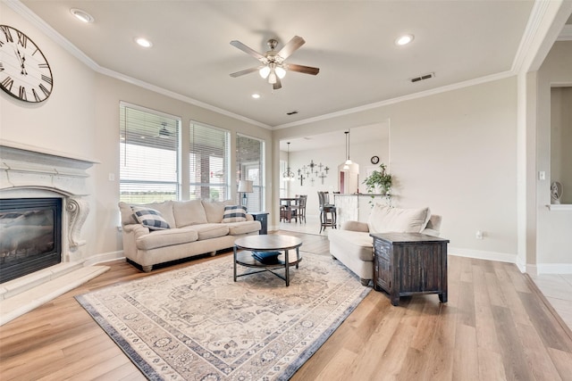 living room featuring a ceiling fan, a fireplace, and light wood-style flooring