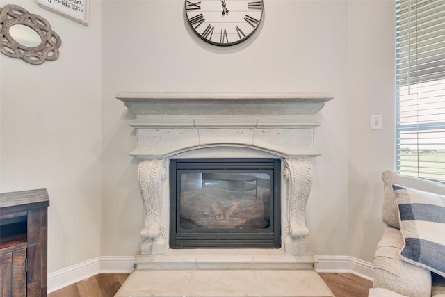interior details with baseboards, a glass covered fireplace, and wood finished floors